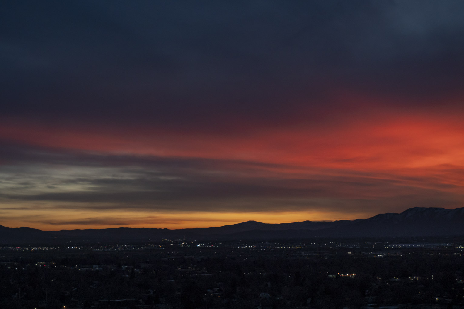 The sun lights a streak of clouds red over town